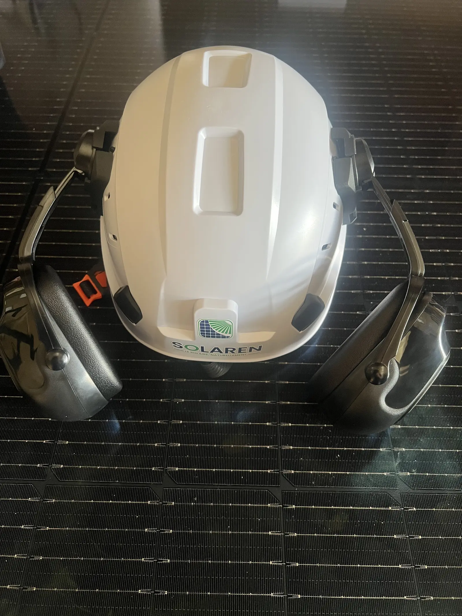 Casque de chantier siglé Solaren posé sur un panneau solaire