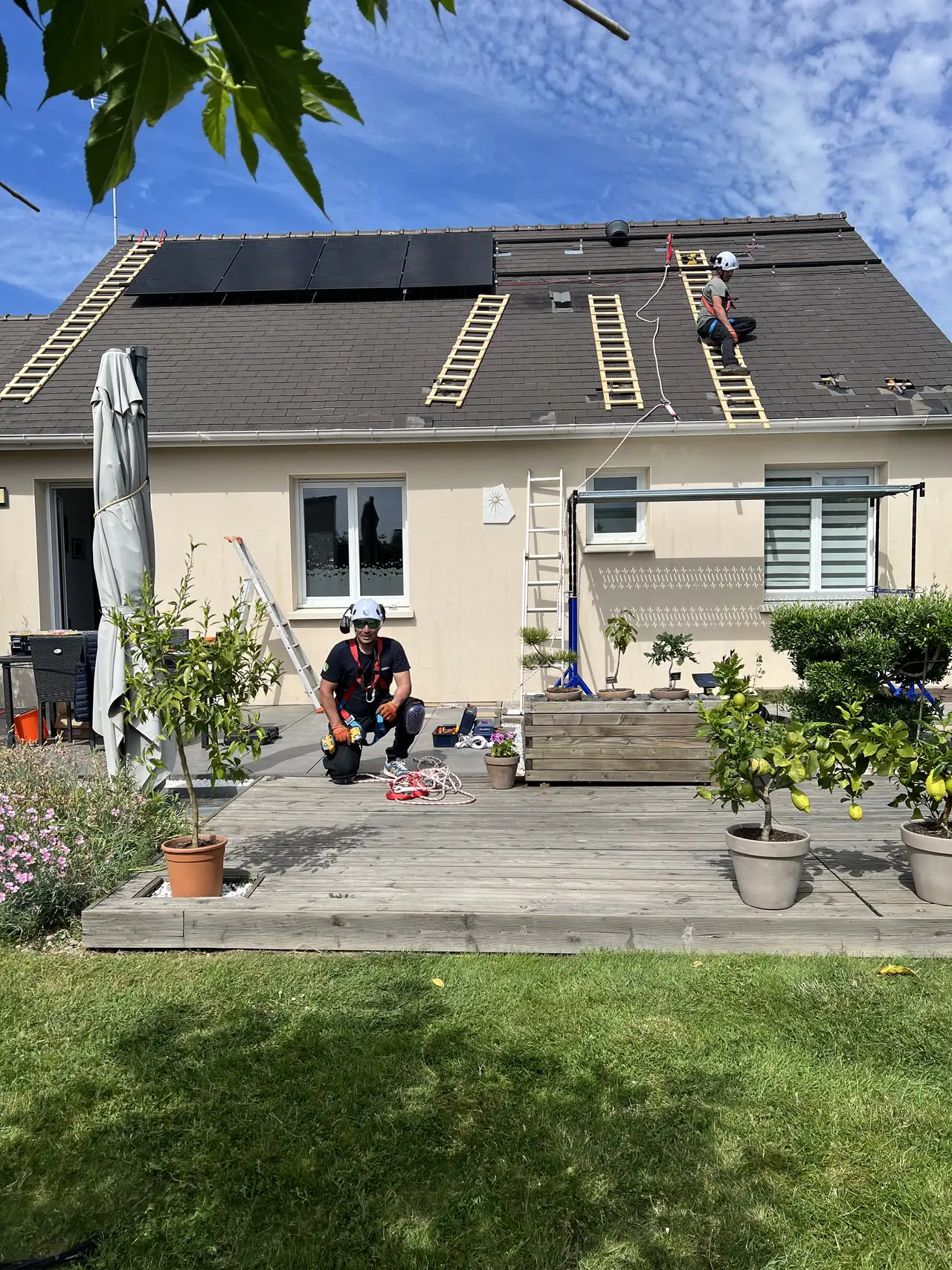 Chantier Solaren en cours : installateur casqué sur la terrasse, panneaux en pose sur le toit